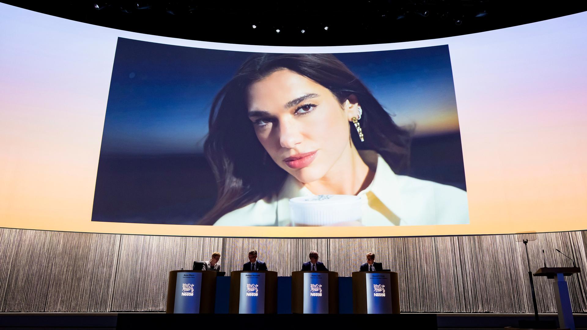 Ein großer Bildschirm mit einem Bild von Dua Lipa bei der Vorstellung der Werbekampagne für Nespresso Ein großer Bildschirm mit einem Bild von Dua Lipa bei der Vorstellung der Werbekampagne für Nespresso