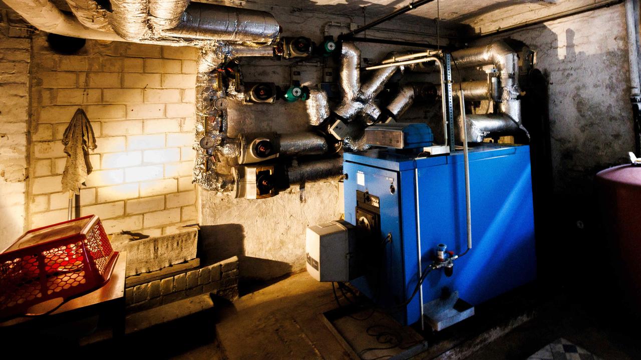 Rohre einer Anlage einer Ölheizung in dem Keller eines Altbaus. Daneben auch der blaue Kessel der Ölheizung.