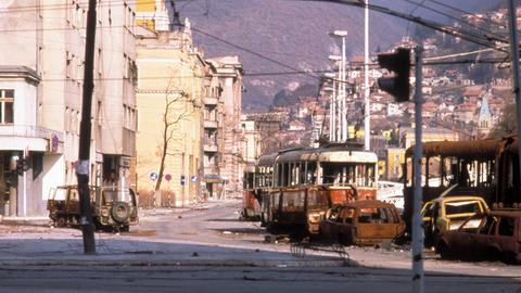 Straße mit zerstörten Straßenbahnwaggons und Autos in Sarajevo 1993.