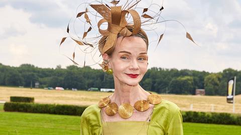 Britt Kanja beim Fashion Weekend auf der Galopprennbahn Hoppegarten in Berlin. Sie trägt ein grünes Kleid und einen auffälligen Hut.