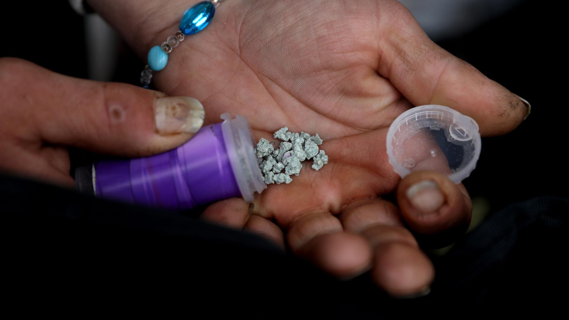 Nahaufnahme von Händen, die Fentanyl-Kristalle in die Kamera halten. Nahaufnahme von Händen, die Fentanyl-Kristalle in die Kamera halten.