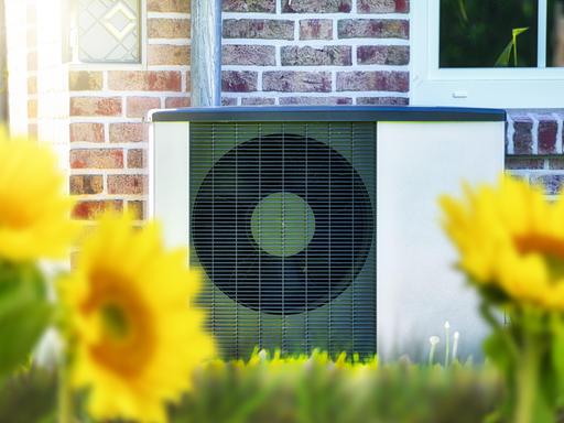 Wärmepumpe vor einem Haus mit Sonnenblumen, Fotomontage