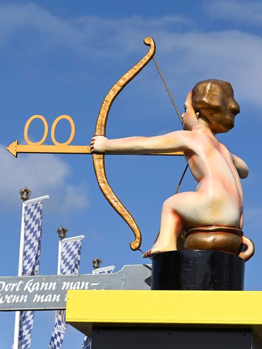 Wegweiser zu den Toiletten vom Oktoberfest 2022 auf der Theresienwiese zeigt einen Jungen auf einem Töpfchen mit Pfeil und Bogen.