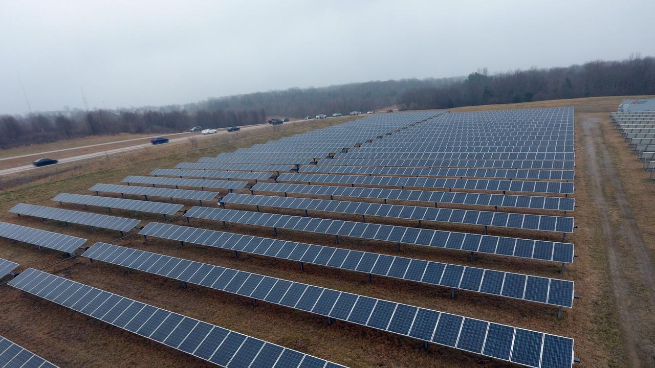 Solarpanele auf einem Feld neben einer Überlandstraße.