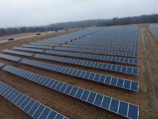 Solarpanele auf einem Feld neben einer Überlandstraße.