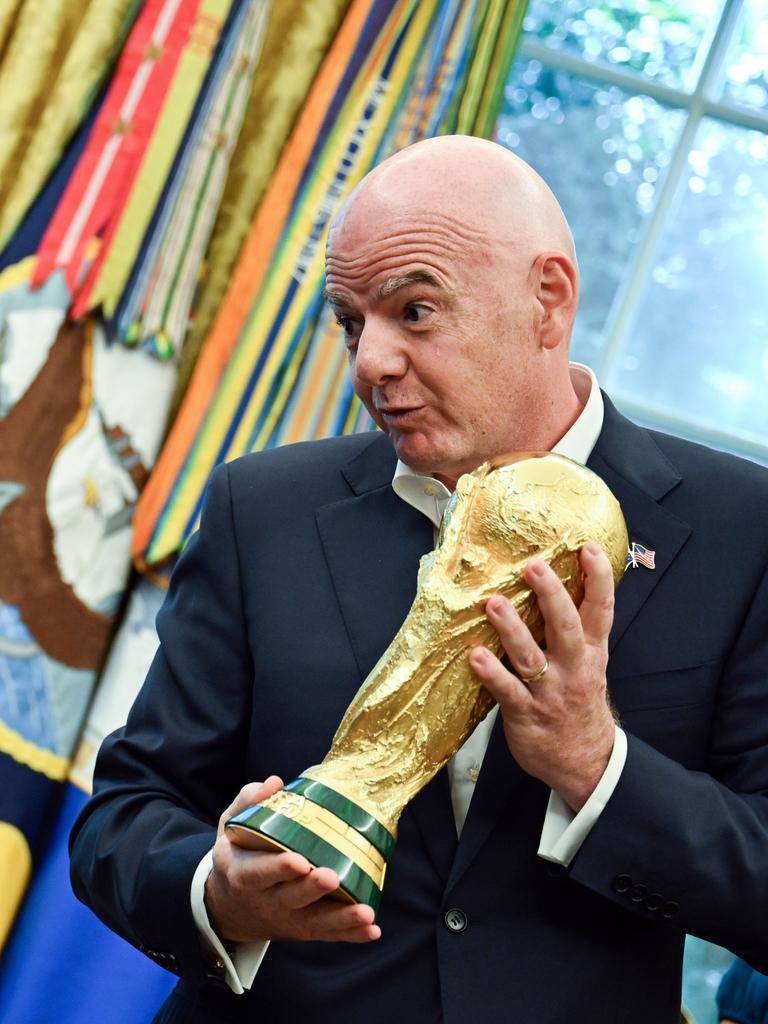 FIFA-Präsident Gianni Infantino hält im Oval Offive den goldenen Fußball-WM-Pokal in den Händen und schaut dabei auf den sitzenden US-Präsident Donald Trump herab. Der trägt eine rote Kappe und grinst zurück. FIFA-Präsident Gianni Infantino hält im Oval Offive den goldenen Fußball-WM-Pokal in den Händen und schaut dabei auf den sitzenden US-Präsident Donald Trump herab. Der trägt eine rote Kappe und grinst zurück.