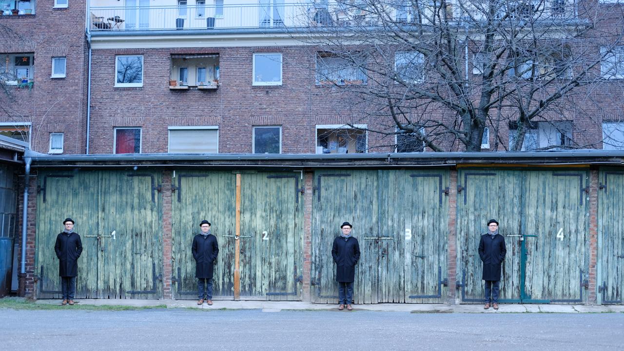 Eine Bildmontage von einem Mann mit Hut, der vier Mal vor einer reighe von vier Garagentoren steht