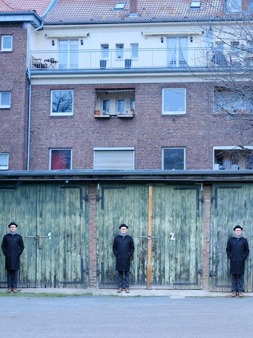 Eine Bildmontage von einem Mann mit Hut, der vier Mal vor einer reighe von vier Garagentoren steht