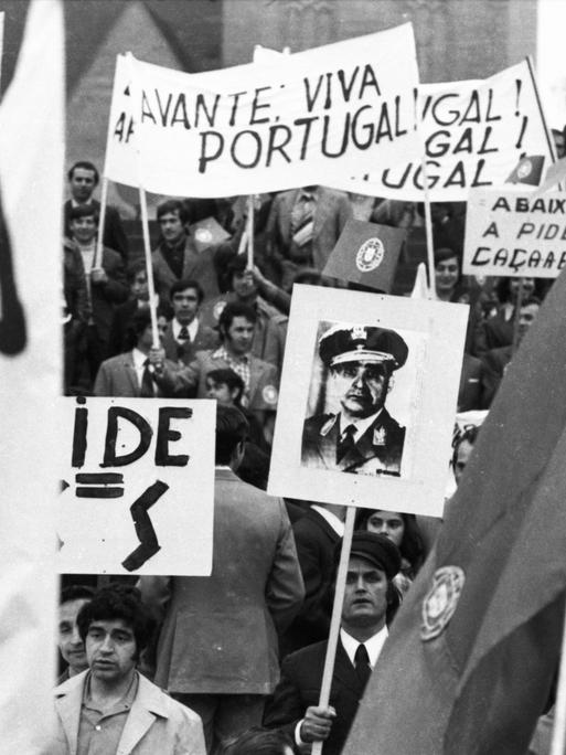 Ein schwarz-weiß Foto einer Demonstration in Dortmund für die Demokatie in Portugal aus dem Jahr 1974. Menschen halten Plakate in die Höhe.