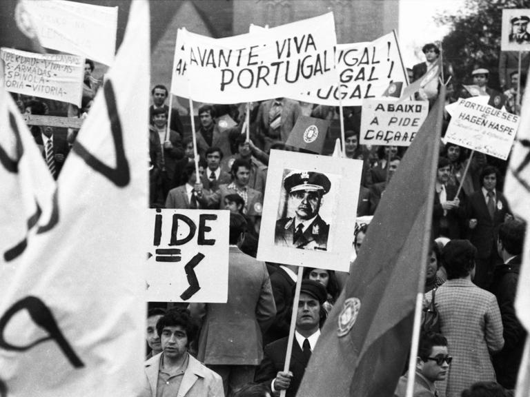 Ein schwarz-weiß Foto einer Demonstration in Dortmund für die Demokatie in Portugal aus dem Jahr 1974. Menschen halten Plakate in die Höhe.