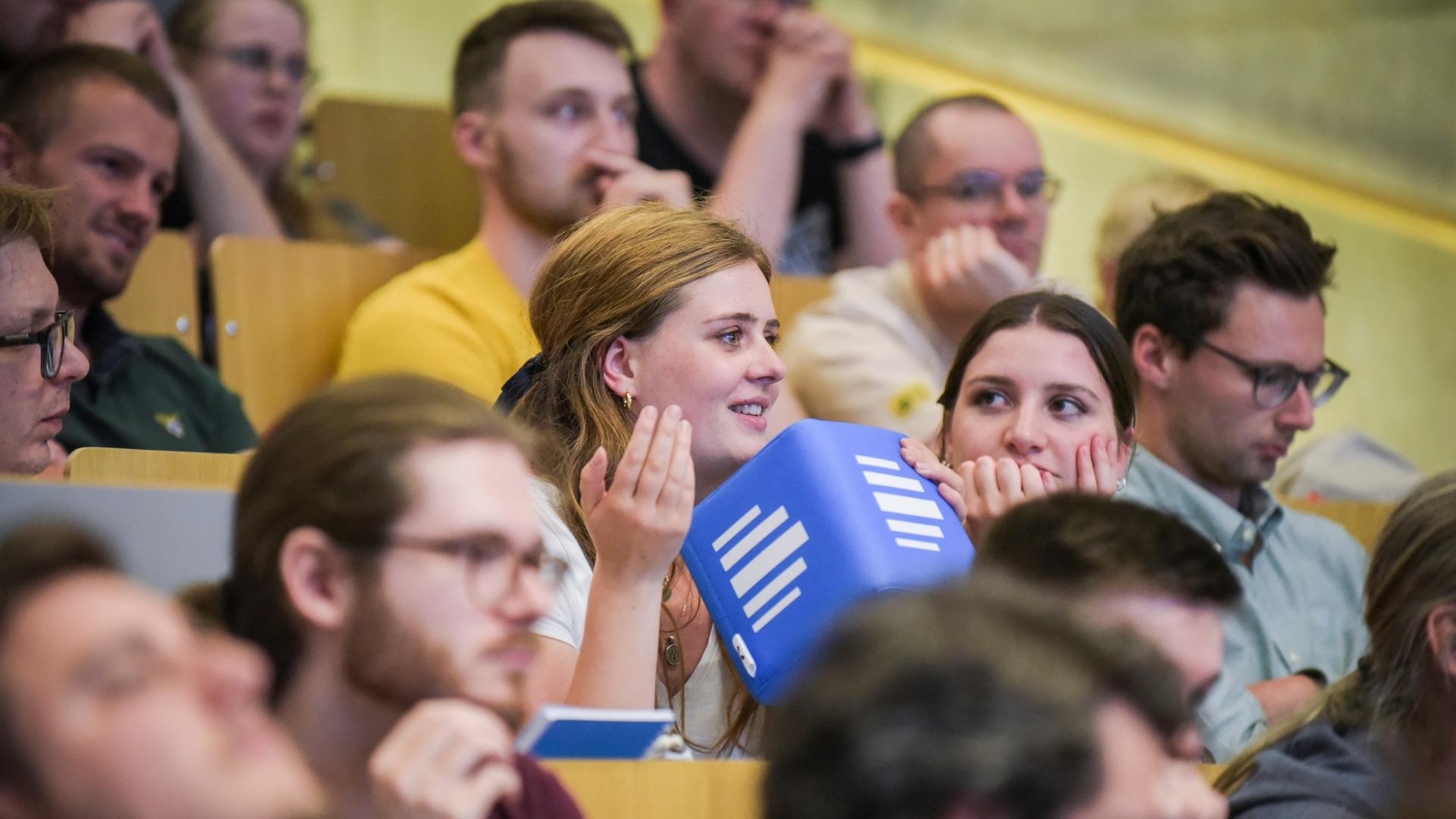 Eine Besucherin der Politikpodcast-Liveaufzeichnung in Duisburg stellt eine Frage in ein würfelförmiges Deutschlandfunk-Wurfmikrofon.