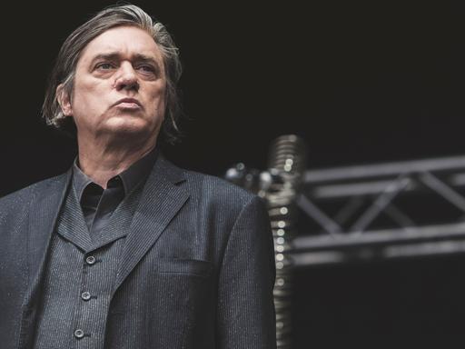 Blixa Bargeld, Frontmann der Band Einstürzende Neubauten", schaut bei einem Konzert in Kopenhagen 2018 von der Bühne ins Publikum.