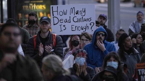 Menschen protestieren in Minneapolis gegen die Einsätze der ICE-Behörde und halten Transparente hoch. 