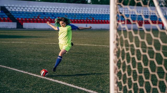 Eine junge Frau schießt gegen einen Fußball