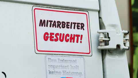 "Mitarbeiter gesucht!" steht auf einem Schild am Transporter eines Handwerksbetriebs für Heizung und Sanitär.