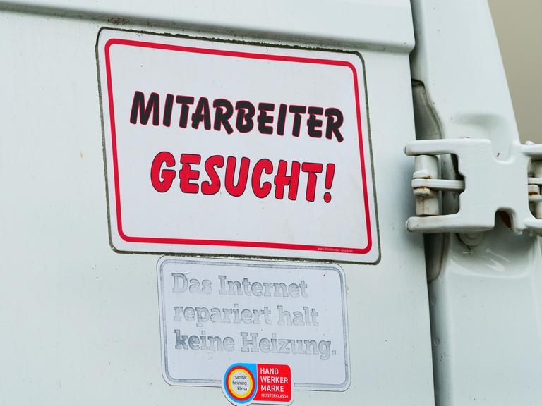 "Mitarbeiter gesucht!" steht auf einem Schild am Transporter eines Handwerksbetriebs für Heizung und Sanitär.