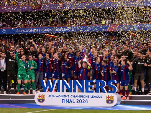 Die Spielerinnen des FC Barcelona feiern den Gewinn der Women's Champions League auf dem Rasen.