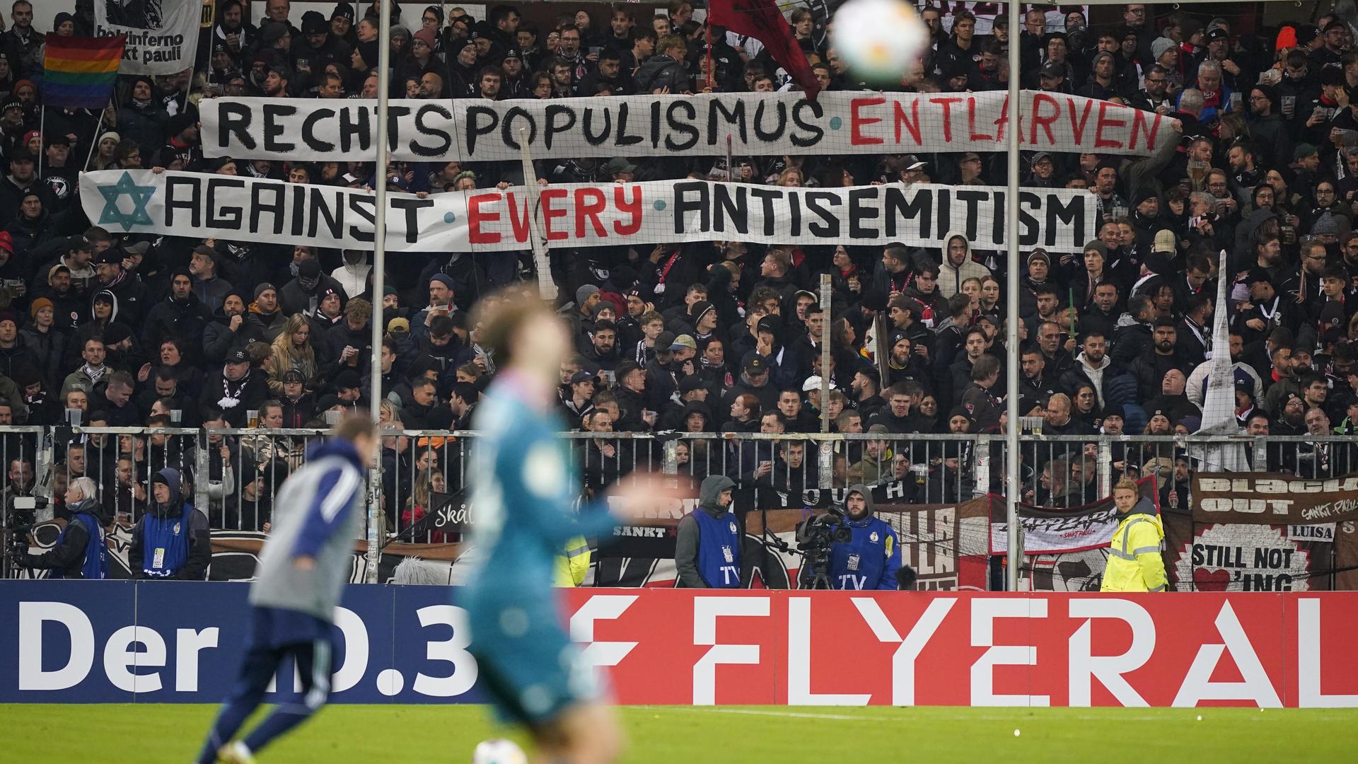 Beim Bundesliga-Spiel FC St. Pauli gegen den FC Schalke halten St.-Pauli-Fans ein Banner hoch mit der Aufschrift "Rechtspopulismus entlarven - against every antisemitism."