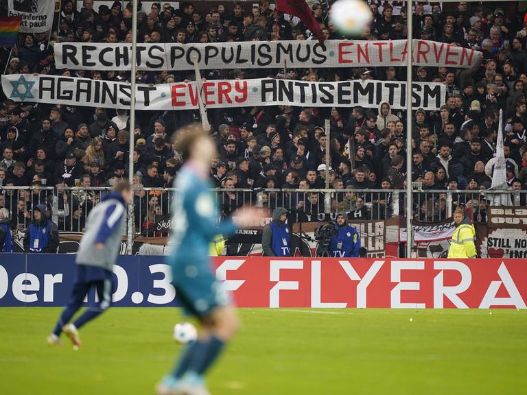 Beim Bundesliga-Spiel FC St. Pauli gegen den FC Schalke halten St.-Pauli-Fans ein Banner hoch mit der Aufschrift "Rechtspopulismus entlarven - against every antisemitism."