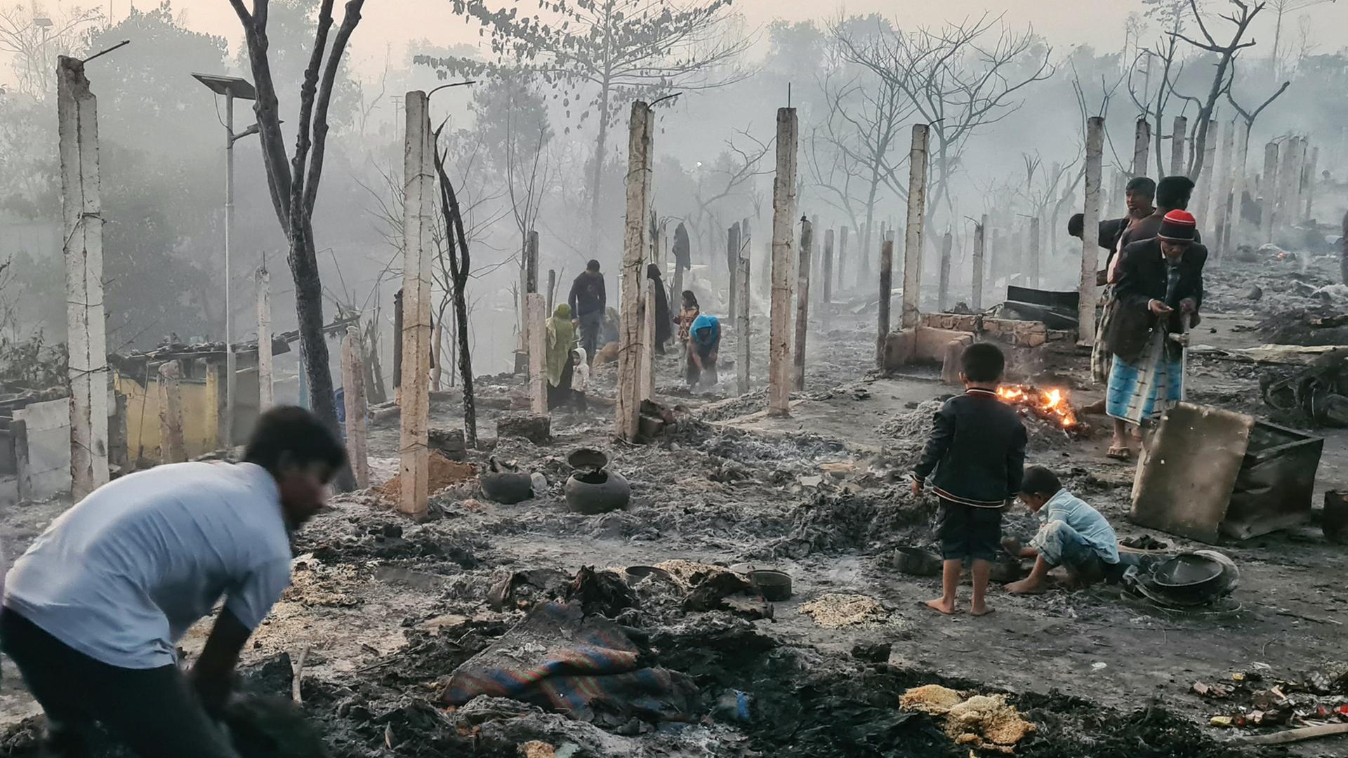 Rohingya suchen in den niederbrannten Überresten eines Flüchtlingslagers nach Habseligkeiten.