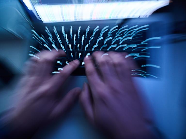 Hände tippen auf einer Computer-Tastatur.