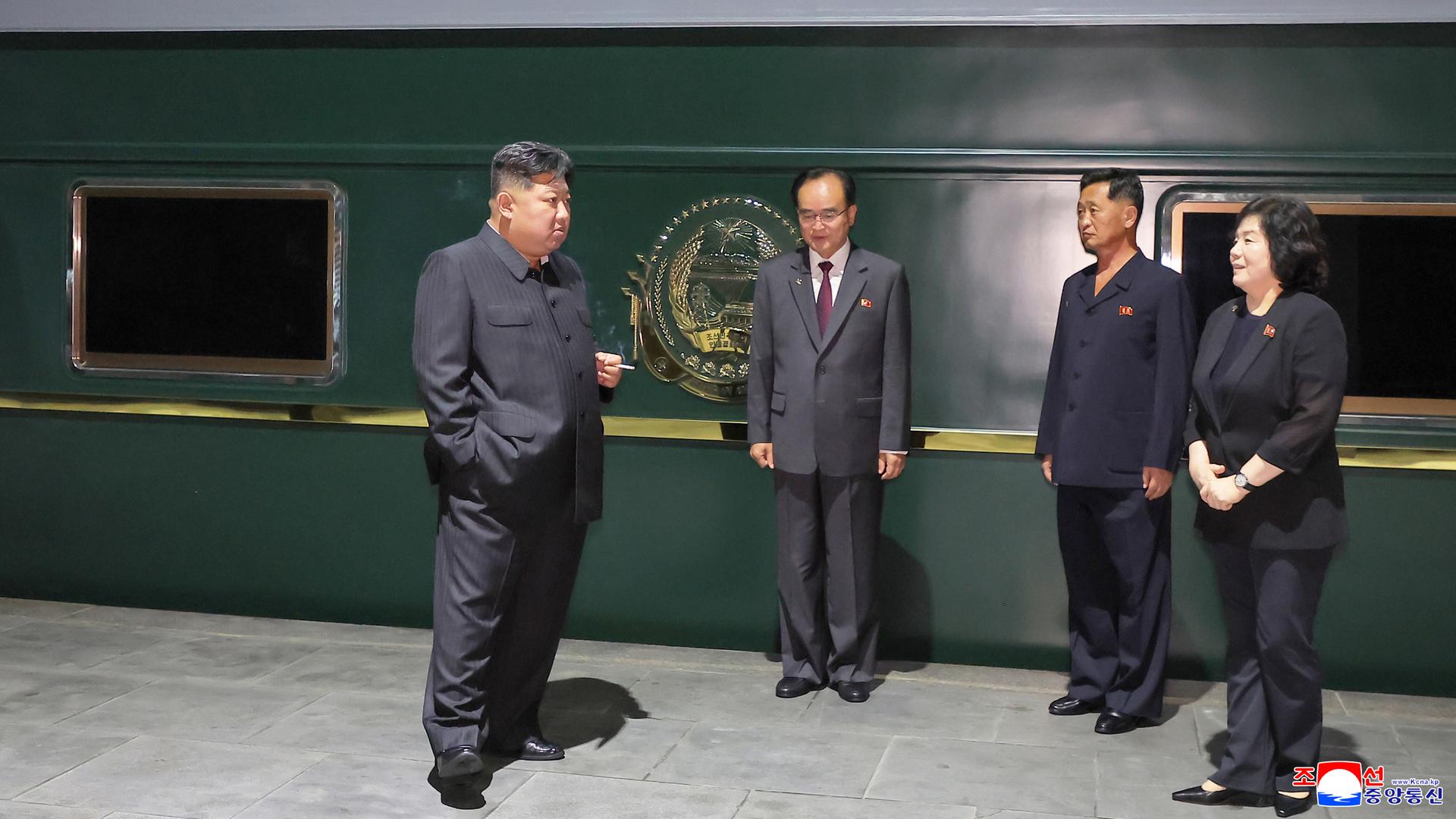 Kim Jong-un steht mit nordkoreanischen Funktionären vor seinem gepanzerten grünen Zug