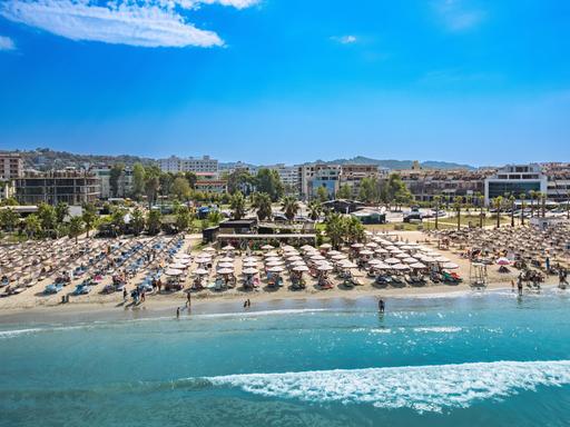 Blick auf einen Strand in Albanien, an dem tausende Sonnenschirme aufgespannt sind und zahlreich Touristen baden.