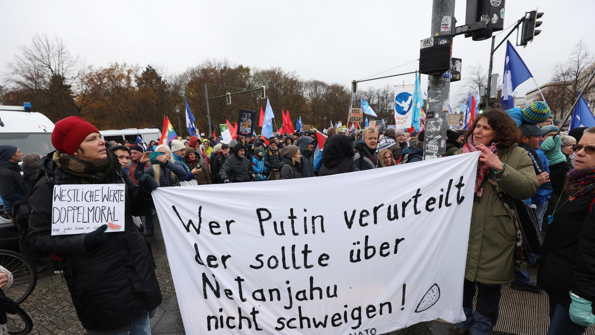 Putinfreundliche Friedensdemonstration im November 2023: Demonstranten halten ein Banner mit der Aufschrift: Wer Putin verurteilt der sollte ueber Netanjahu nicht schweigen. Unter dem Motto: Nein zu Kriegen - Rüstungswahnsinn stoppen.