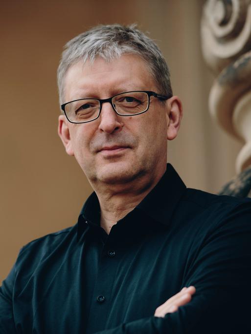 Hans-Christoph Rademann steht neben einer barocken Fassade und schaut freundlich in die Kamera.