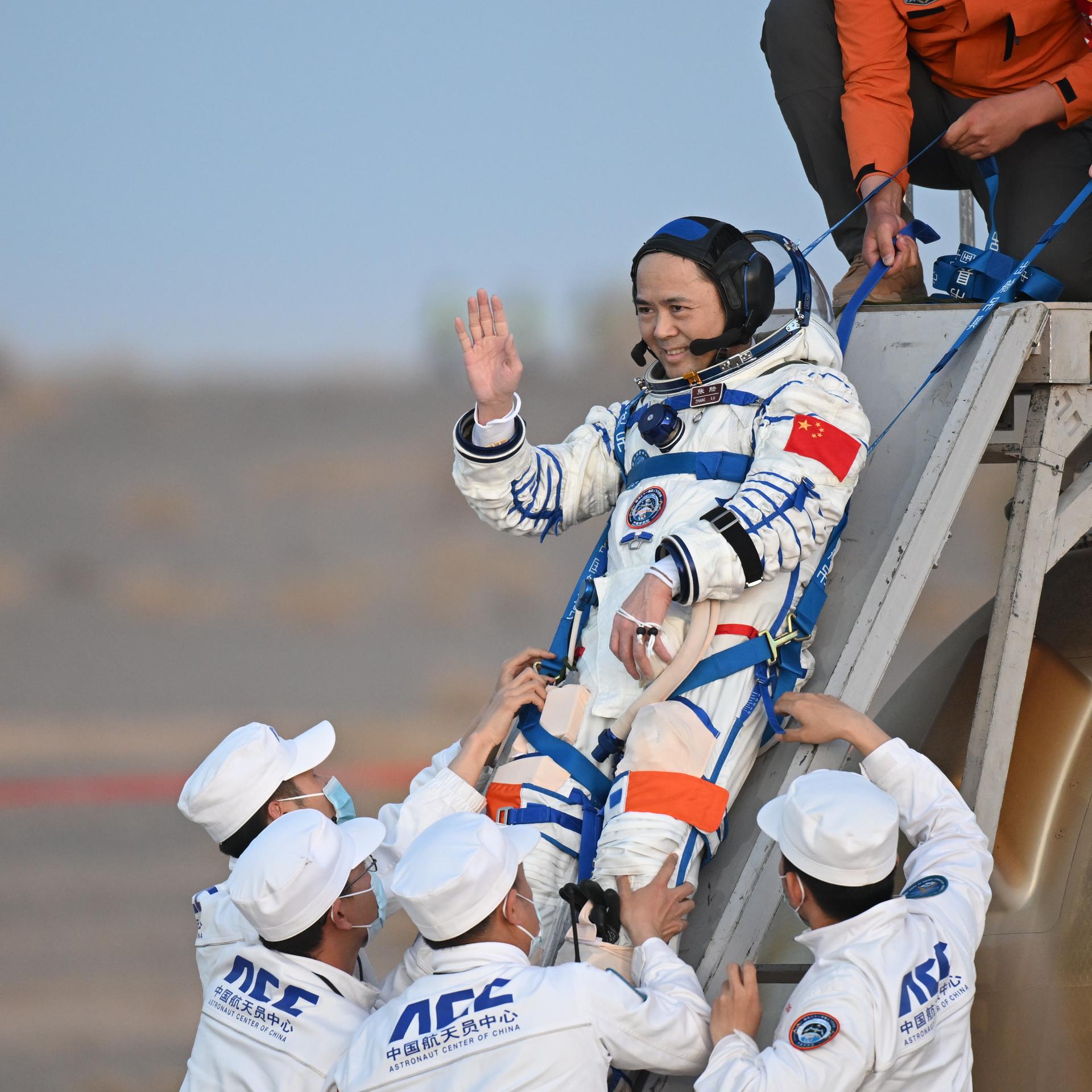 Mehrere Menschen helfen einem Astronauten beim Ausstieg aus der Landekapsel. 