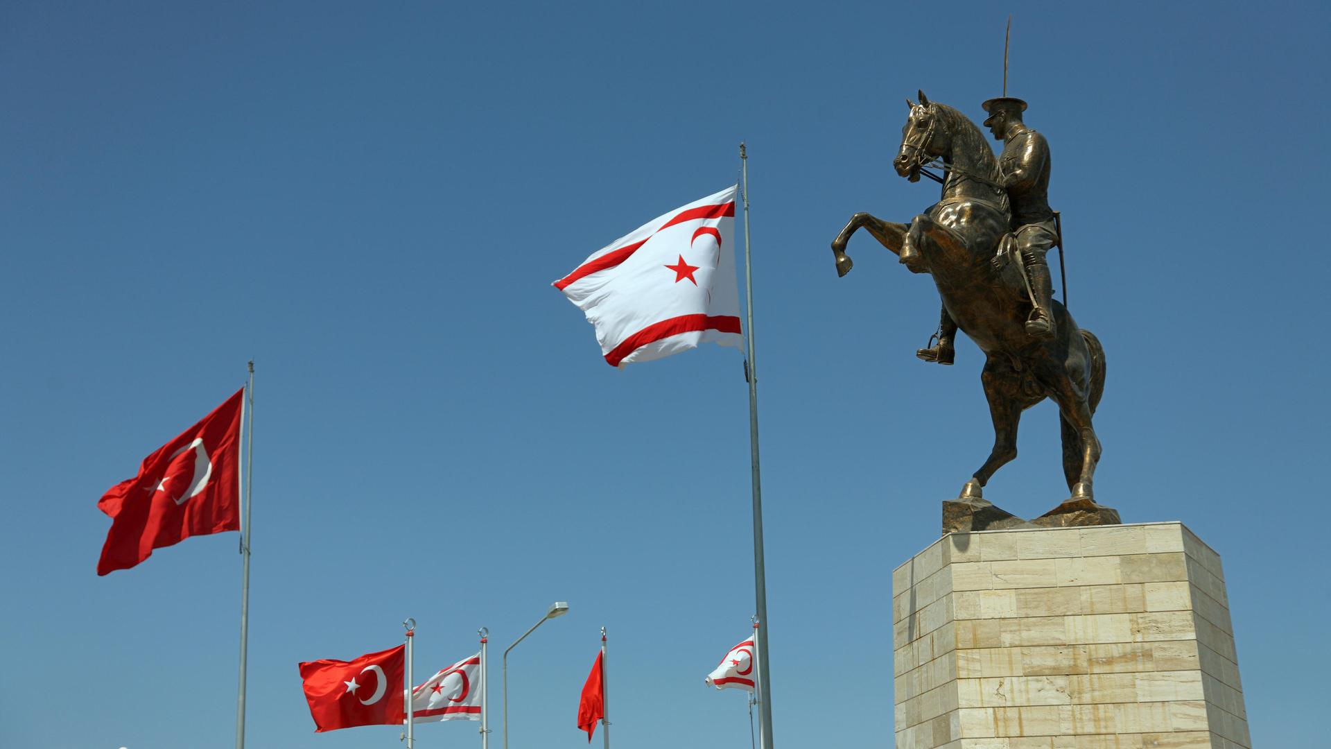 Statue des türkischen Staatsgründers Atatürk auf einem Pferd. Daneben sind türkisch und nordzyprische Nationalflaggen zu sehen.
