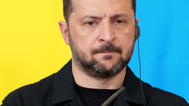 Ukraines Präsident Selenskyj steht vor einer ukrainischen Flagge.