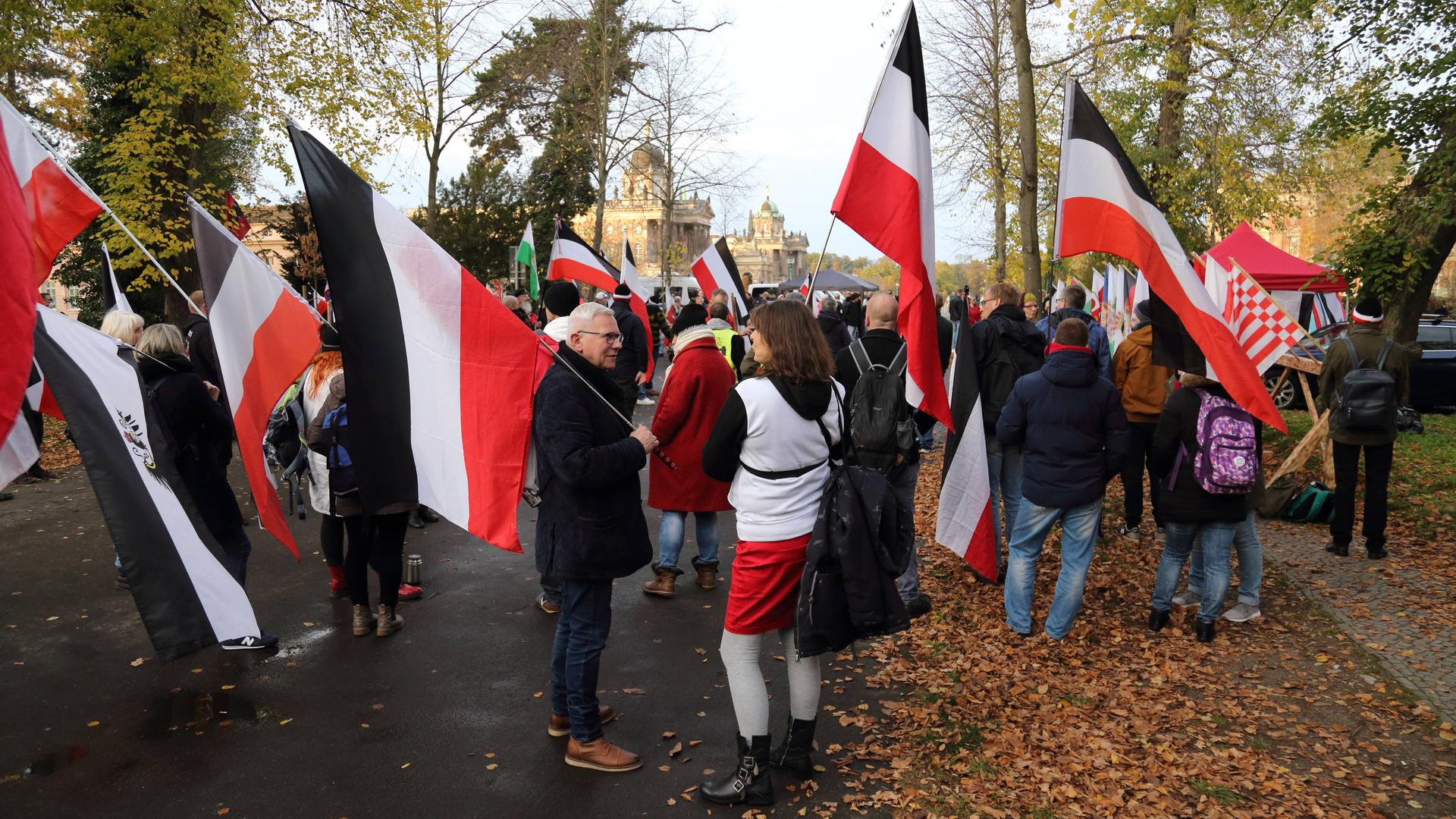 Teilnehmer mit schwarz-weiß-roten Reichsflaggen während einer Demonstration von Reichsbürgern und anderen Rechtsextremen für die Wiedereinführung der Monarchie am Neuen Palais in Potsdam. 
