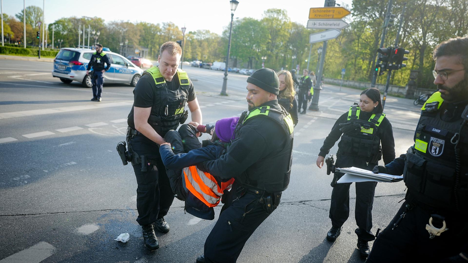 Polizeibeamte tragen eine Klimaaktivistin von der Straße am Großen Stern vor der Siegessäule.