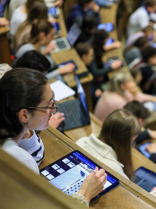 Medizinstudenten sitzen im Hörsaal Anatomie in einer Vorlesung. Im Vordergrund eine junge Frau mit I-Pad. 