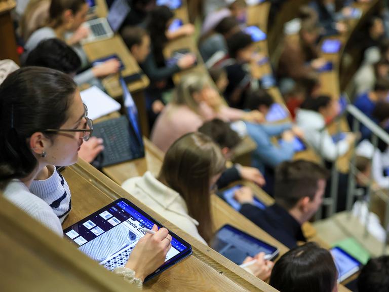 Medizinstudenten sitzen im Hörsaal Anatomie in einer Vorlesung. Im Vordergrund eine junge Frau mit I-Pad. 