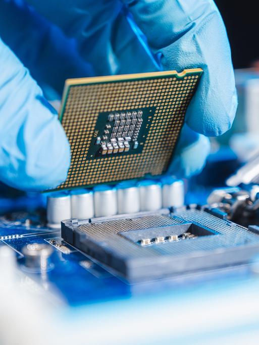 Halbleiter-Produktion: Nahaufnahme einer Hand, die eine CPU (Central processing unit) einsetzt.
