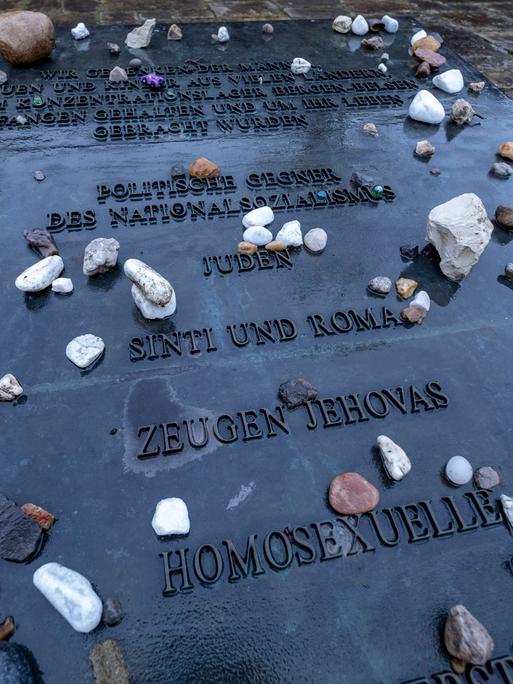 Auf einer grauen Gedenktafel sind Opfergruppen des Nationalsozialismus aufgelistet, u.a. Juden, Zeugen Jehovas, Homosexuelle