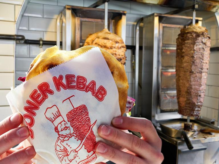 Ein Frisch zubereiteter Döner Kebab in der Hand eines Kunden