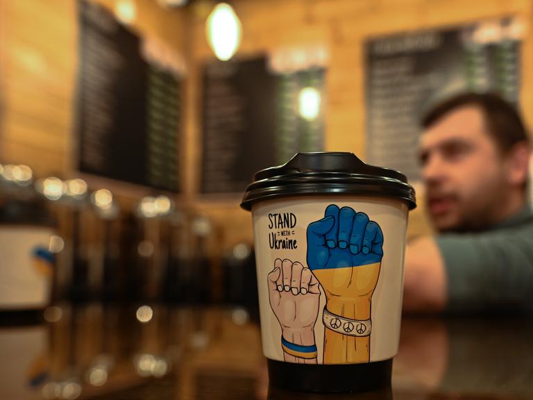 Ein Kaffeebecher mit symbolischen Bildern und der Aufschrift "Stand with Ukraine" in einem Cafe in der westukrainischen Stadt Chmelnyzkyj