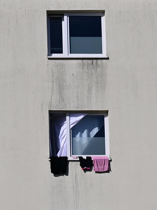 Die Landeserstaufnahmeeinrichtung auf dem Suhler Friedberg. Eine triste graue Häuserfassade mit Fenstern, aus denen einige Kleidungsstücke heraushängen. 