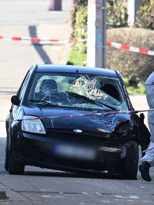 Beamte der Spurensicherung untersuchen ein beschädigtes Fahrzeug an einer Zufahrt zur Rheinbrücke. 