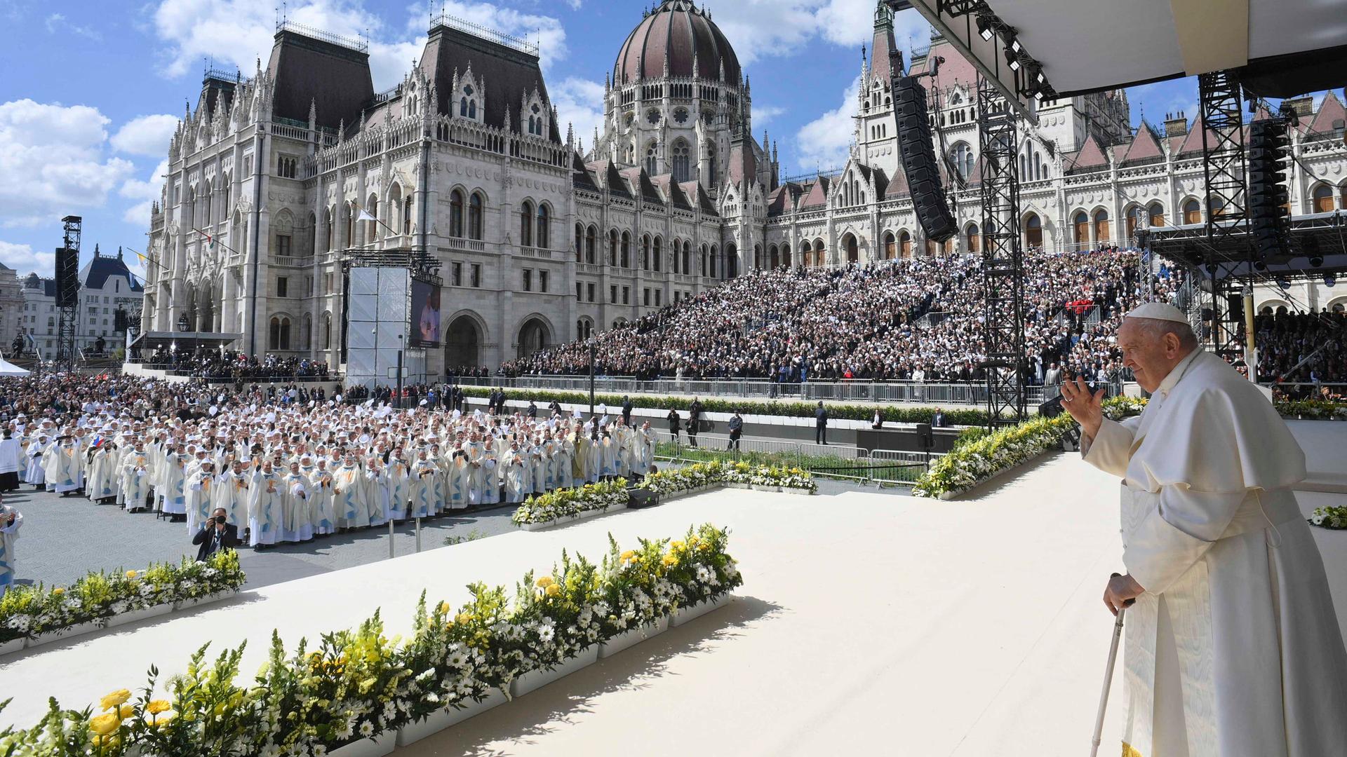 Papst Franziskus steht auf der Bühne und begrüßt die Teilnehmer der Messe in Budapest.