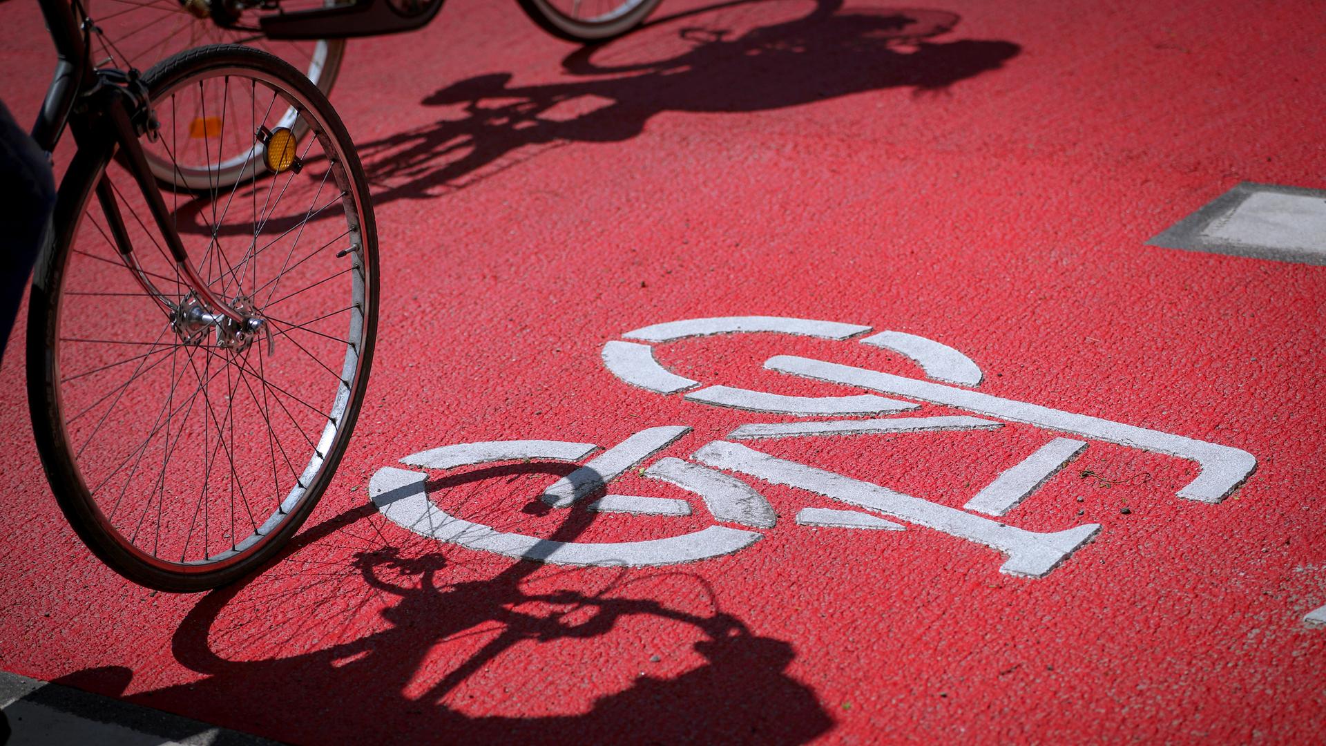 Auf einem Fahrradweg fährt ein Fahrrad, das Vorderrad fährt über das Fahrradsymbol. 