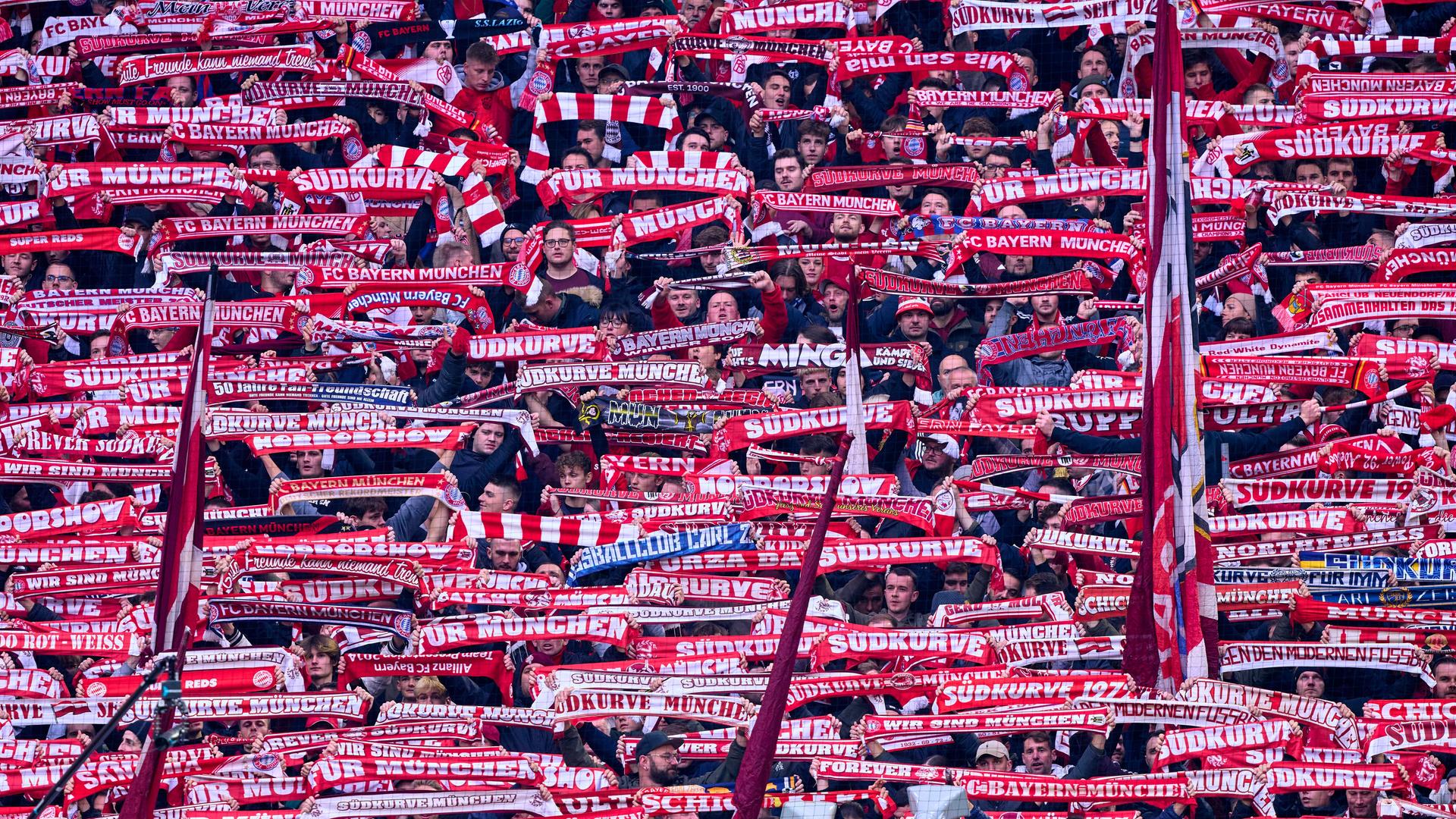 In der Südkurve des Münchner Stadions halten Bayern-Fans rote Schals nach oben.