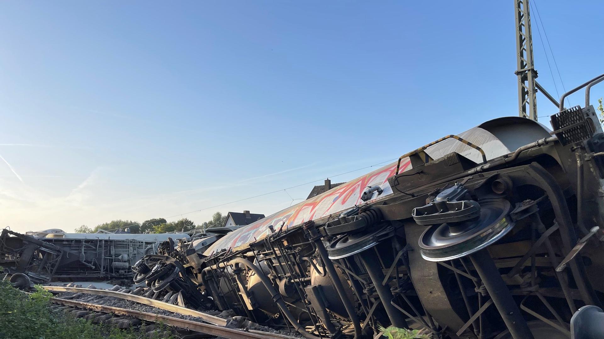 Eine Lokomotive und mehrere Güterwaggons sind entgleist und liegen auf der Seite. Eine Lokomotive und mehrere Güterwaggons sind entgleist und liegen auf der Seite.