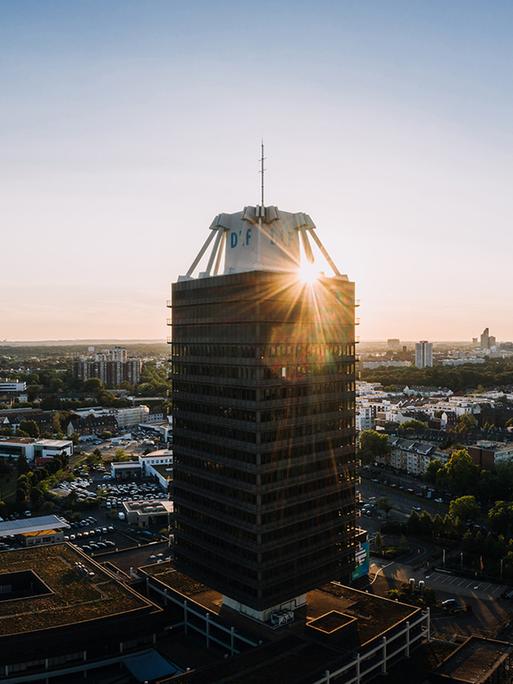 Das Hochhaus des Deutschlandfunks in einer Luftaufnahme mit untergehender Sonne im Hintergrund.