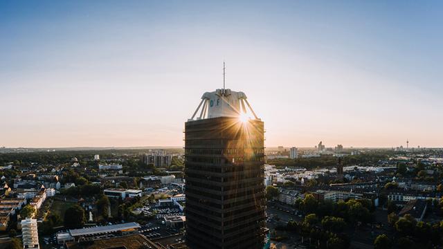 Das Hochhaus des Deutschlandfunks in einer Luftaufnahme mit untergehender Sonne im Hintergrund.