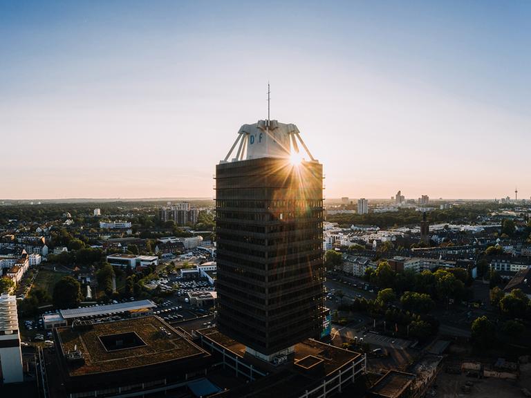 Das Hochhaus des Deutschlandfunks in einer Luftaufnahme mit untergehender Sonne im Hintergrund.