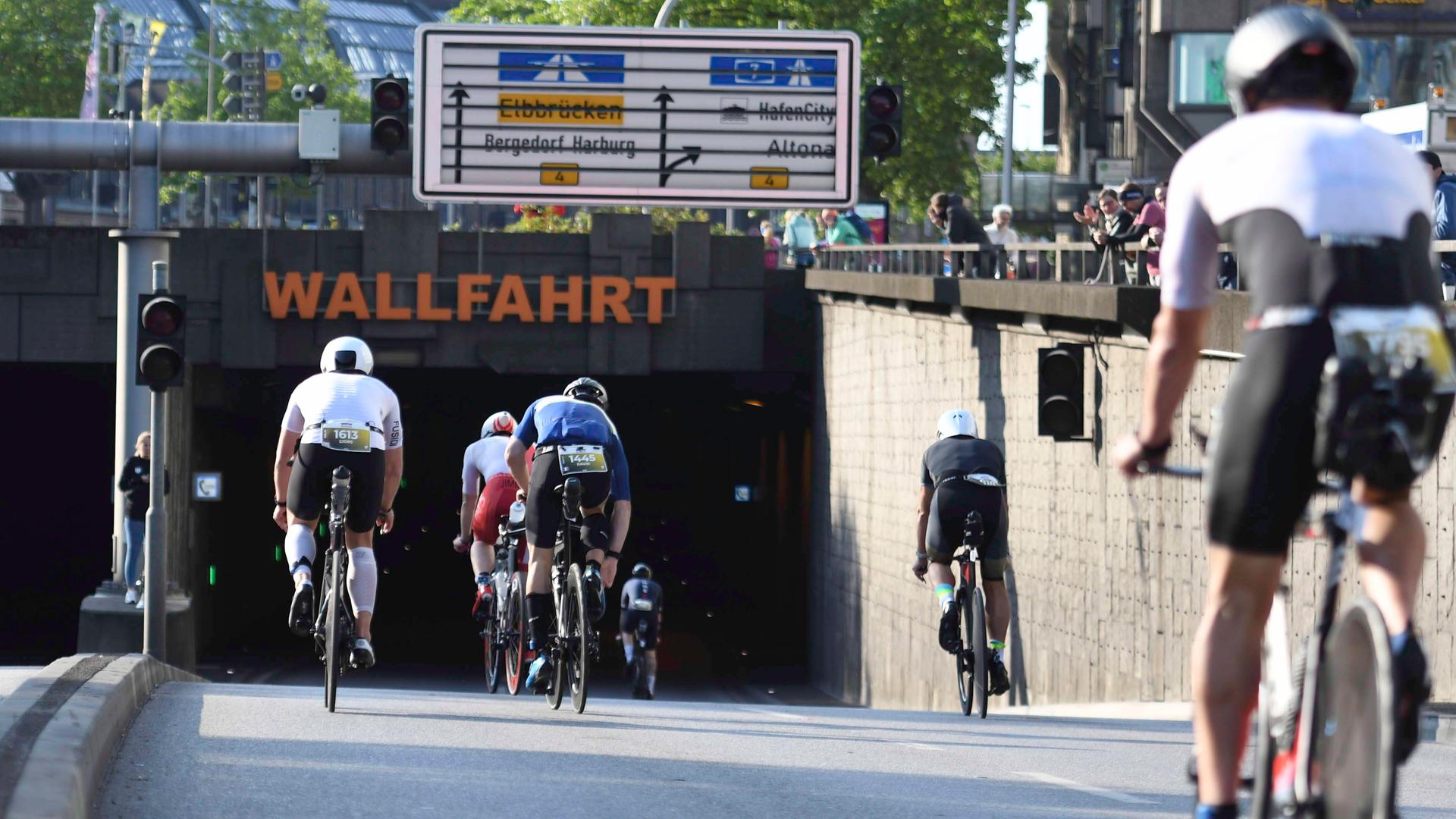 Teilnehmer des Ironman-Rennens in Hamburg fahren auf ihren Fahrrädern an der Kunsthalle in einen Tunnel. 